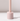 The Hall of Flame Ballet Pink Wax Candle Holder, made from sustainable plant-based wax in a pale pink cylindrical design with a vertical rod, stands on a white surface and casts a soft shadow against a plain light background.