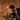 A man in a suit leans over a round table with three lit Hall of Flame Black Plated Candle Holders, appearing to blow one out. A hand lowers a glass cylinder over the flames, showcasing careful candle holder care against a textured backdrop.