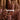 Four large Hall of Flame Dusty Rose Pillar Candles XXL are lit amid clusters of pink orchids. CAPPUCCINO appears in bold text, set against warm brown curtains with “HALF OF FLAME.” displayed above.