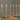 The Hall of Flame Straight Set Bundle features beige plates, silver cutlery, and six tall cathedral candles in disposable wax holders, all arranged on a white tablecloth—ideal for minimalist wedding dining.
