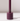The Hall of Flame Jam Purple Wax Candle Holder features a cylindrical design with a central vertical rod, ideal for sustainable plant-based pillar candles. It casts a soft shadow on white surfaces against light backgrounds.
