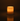 The Hall of Flame Pillar with Wax Sleeve glows warmly in a dark room, its gentle flame illuminating the space and casting a soft reflection on the smooth surface beneath its elegant wax sleeve.