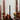 A moody table setting with tall black candles in Hall of Flame Black Wax Candle Holders, brown roses, figs, a yellow flower in a small vase, and tinted glass cylinders set against a neutral background.