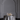The Hall of Flame Round Table is topped with a white satin cloth, set with the Pillar Cluster candle display and two champagne glasses, and adorned with a bouquet before a large empty arch on a gray wall.