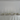 The Antique Wedding Bundle by Hall of Flame features white plates, silver cutlery, napkins, tall white candles in silver holders, and small white florals on a white tablecloth against a plain wall—perfect for minimalist elegance.