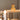 A yellow two-tier cake topped with cherries rests on a table surrounded by Hall of Flame Round | Crystal Glass Votive Holders, their candlelight softly illuminating the scene with blurred decor in the foreground.