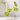 Five white candles in the Hall of Flame Glass Crystal Candelabra are accented with five green anthurium stems, all set against a plain white backdrop.