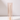 A tall, white taper candle stands upright in a Hall of Flame Nude Coloured Glass Sleeve, adding a modern touch to classic holders. Displayed on a white surface against a simple background.