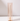 A tall, white taper candle stands upright in a Hall of Flame Nude Coloured Glass Sleeve, adding a modern touch to classic holders. Displayed on a white surface against a simple background.
