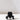 The SAMPLE | Black Flower Holder by Hall of Flame sits on a white surface, its sculptural design casting a shadow. Made from fire-retardant polycarbonate using 3D print technology, this striking piece stands out against the light background.