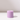 A cylindrical, light purple candle sits on a white surface against a pale background, casting a gentle shadow—ideal for pairing with the Hall of Flame Wisteria Purple Wax Candle Holder.