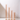 Four beige candles in tall Hall of Flame candle holders, each featuring a Nude Coloured Glass Sleeve, are arranged in descending order from left to right on a white surface with a light background.