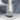 A close-up of a clear cylindrical Acrylic Base Plate by Hall of Flame with a white rod inside, casting soft shadows on a light gray surface. This elegant design helps prevent wax spills.