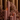 Four XXL Dusty Rose pillar candles by Hall of Flame are lit and grouped together, surrounded by pink and white orchids. Beige curtains hang in the background.