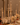 A candlelit dinner table set with tall white candles, cream roses, champagne bottles, gold cutlery, glassware, and small orange fruits on a white tablecloth.