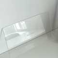 A clear, rectangular Acrylic Candle Drip Tray by Hall of Flame is displayed on a white shelf against a white wall, with the brand name faintly visible and a window reflection on the tray.