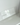 A clear, rectangular Acrylic Candle Drip Tray by Hall of Flame is displayed on a white shelf against a white wall, with the brand name faintly visible and a window reflection on the tray.