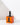 The Hall of Flame Black Plated Candle Holder, designed for XXL Tapers, rests atop an orange box with a matching black silhouette. The scene is brightly lit with distinct shadows on a white background.