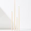 Four Hall of Flame Ivory Ultra-Bright LED Flameless Taper Candles of varying heights stand upright on a white surface against a white background, casting soft shadows.