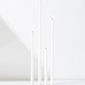 Four Hall of Flame White Realistic LED Flameless Taper Candles of varying heights stand lit and upright on a smooth white surface against a plain white background.