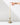 A hand reaches for the flame of a Hall of Flame Ivory Ultra-Bright LED Flameless Taper Candle, displayed in a gold holder on a white surface against a plain white background.