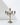 The Hall of Flame 5-arm Antique Gold Candelabra, crafted from alloy metal, boasts five ornate candle holders and a charming vintage look, displayed on a reflective white surface against a light gray background.