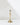 The Hall of Flame Tall | Antique Gold Holder, a single brass candlestick with a slender, elegant design, rests on a white surface. Its classic vintage style and soft shadows highlight its timeless appeal.