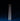 Two white SAMPLE SALE | LED Candles by Hall of Flame stand side by side on a blue surface against a dark background, casting long shadows behind them.