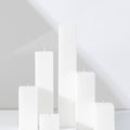 Six Hall of Flame White Square Pillar Candles XXL in various heights are arranged on a white surface.