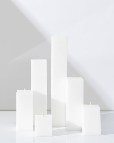 Six Hall of Flame White Square Pillar Candles XXL in various heights are arranged on a white surface.