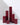 Six Hall of Flame Bordeaux Dark Red burgundy Square Pillar Candles are clustered on a white surface, their burgundy colour.