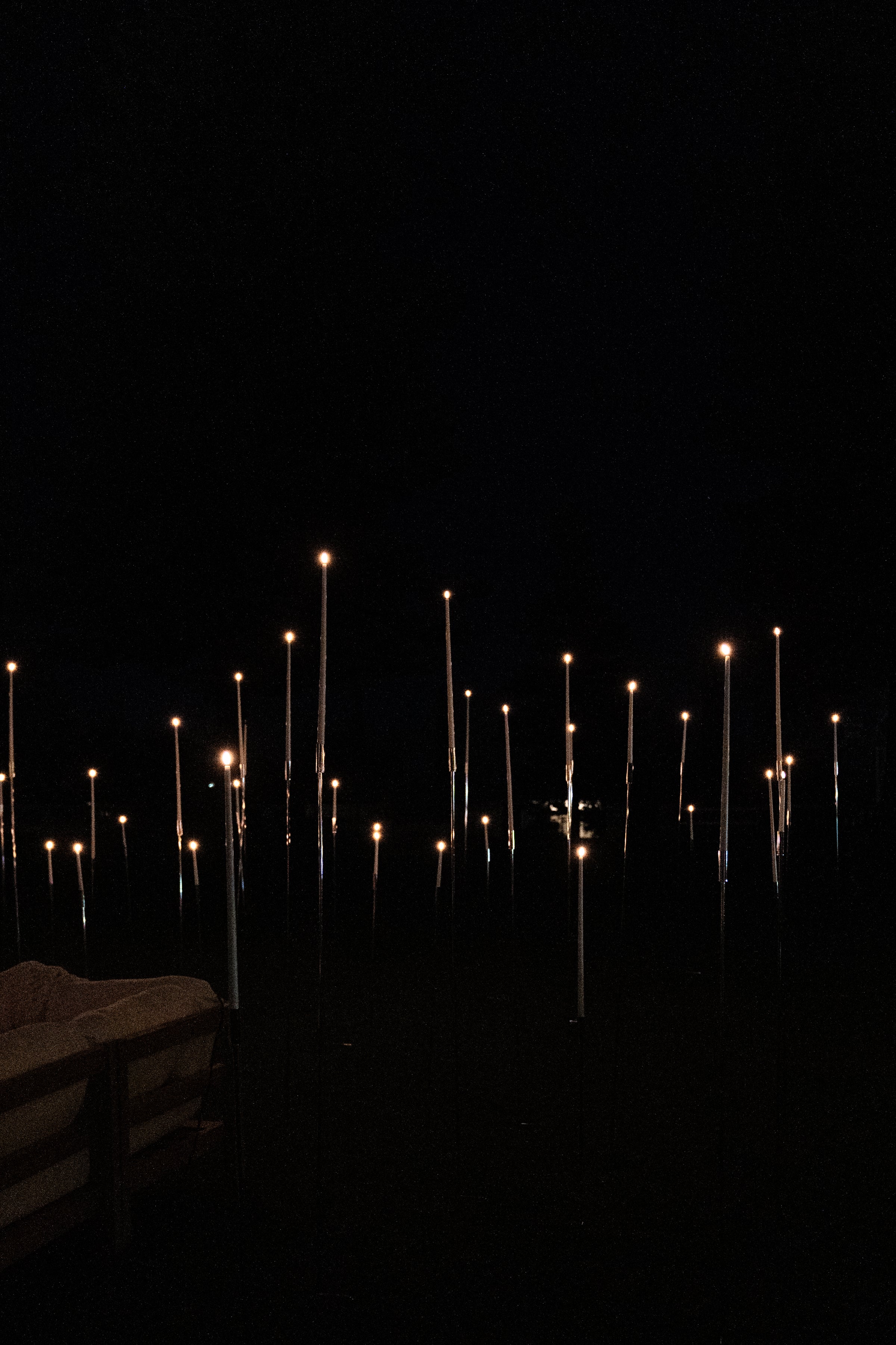 Hall of Flame's 8-in-1 Convertible Candle Holder glows softly at night, creating a floating candle effect. A wooden bench with a blanket in the lower left adds warmth to the ambient scene.