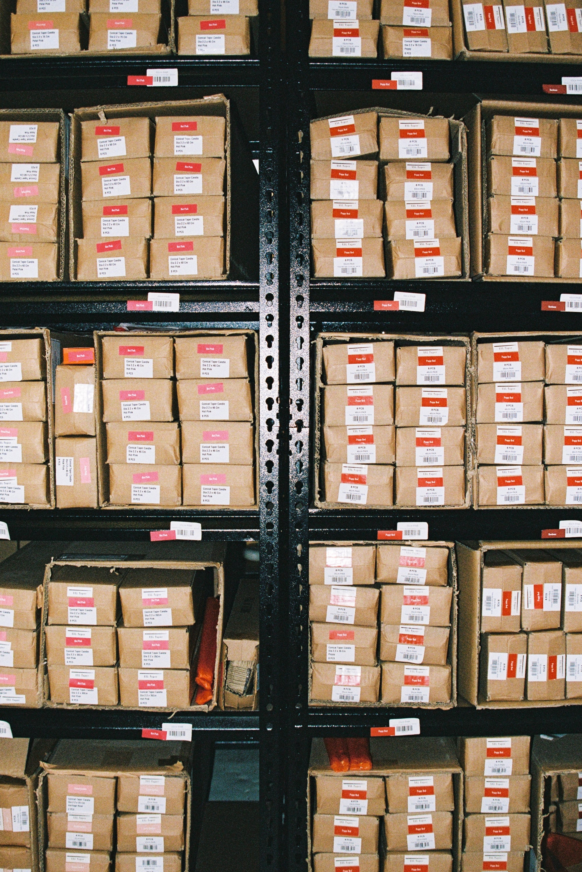 Rows of Hall of Flame Mystery Bundle packages, each marked with white and red tags, are neatly arranged on shelves in a warehouse.
