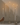 A hand holds a Hall of Flame Remote for Ultra-Bright LED Taper Candles near a silver candelabra with two lit white LED candles, set against a plain light-colored background.