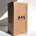 A tall beige candle stands beside a large Hall of Flame “Bulk Candles | Wholesale by-the-box” carton, featuring a vintage archway—ideal for weddings or anyone seeking bulk buy candles from this trusted Australian brand.