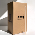A tall beige candle stands beside a large “Hall of Flame” box labeled “Bulk Candles | Wholesale by-the-box,” ideal for anyone seeking affordable bulk candles in Australia, bathed in bright sunlight.