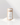A cylindrical kraft paper container labeled SANDWAX Scented Candle Refill by Hall of Flame stands upright on a white surface with small piles of white powder. Its minimalist label features a line drawing of a candle and the scent FIG BOIS.