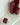 Four burgundy square candles of varying heights sit unlit on a glossy white Acrylic Candle Drip Tray by Hall of Flame near a wall, their reflections visible on the tray’s surface.