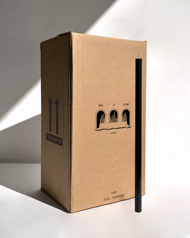 A tall box labeled Hall of Flame Bulk Candles | Wholesale by-the-box stands upright with a single long black candle leaning against it, both casting shadows on a white background—ideal for wholesale candle orders across Australia.
