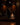 Two people in suits stand on a wooden stage with a drum set and piano nearby. Hall of Flame ULTRABRIGHT™ LED Flameless Taper Candles are arranged in front, creating a warm, intimate atmosphere without open flames.