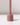 The Hall of Flame Dusty Rose Wax Candle Holder features a minimalistic cylindrical base and tall, narrow stem. It stands on a white surface against a light background, casting a gentle shadow.